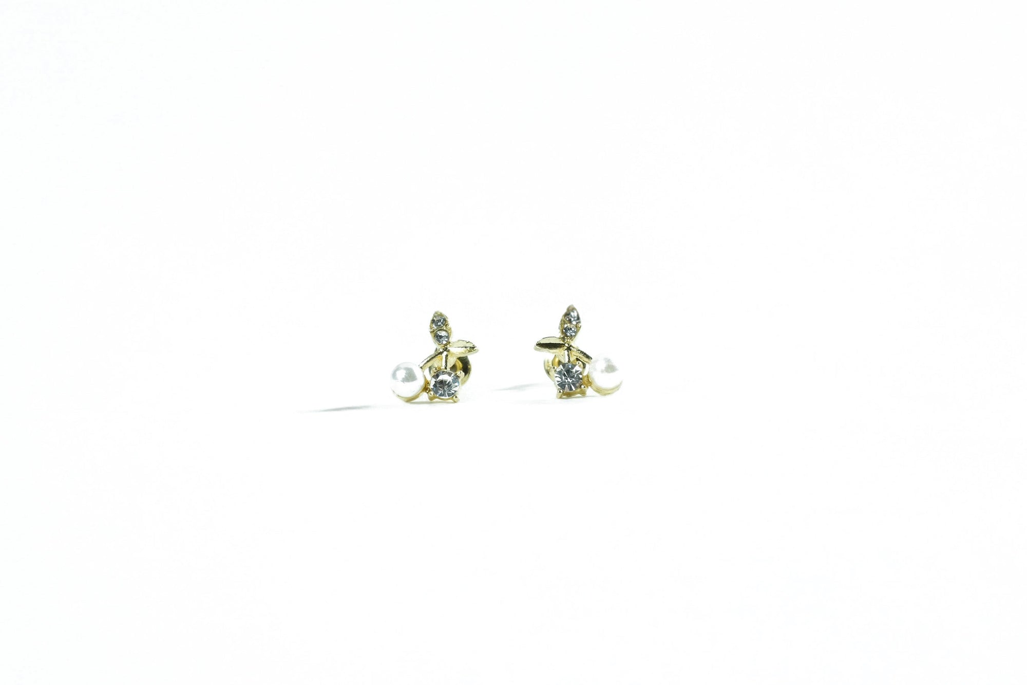 Uniquely designed golden cherry earrings with pearl and zirconia, a refined accessory.